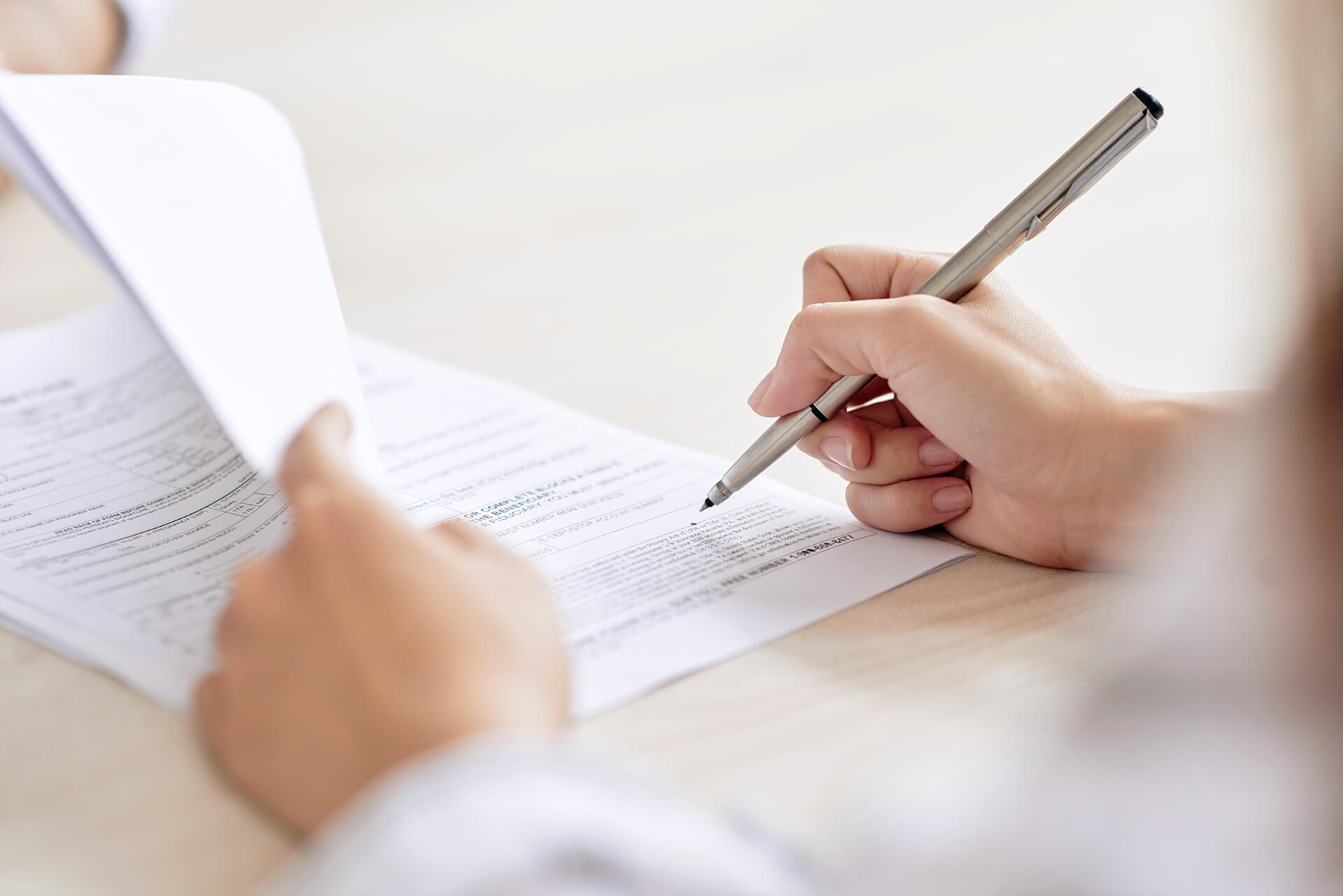 A person writing on paper with a pen.