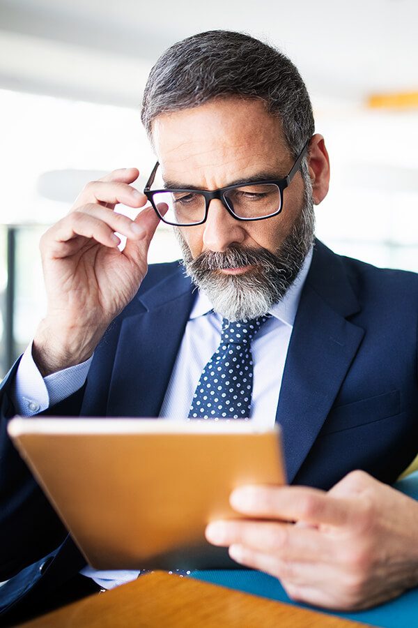 A man in a suit and tie looking at an ipad.