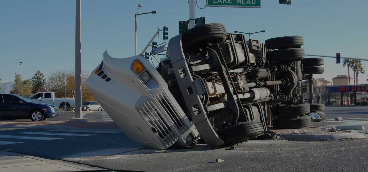 A truck that has been flipped over on the side of a road.