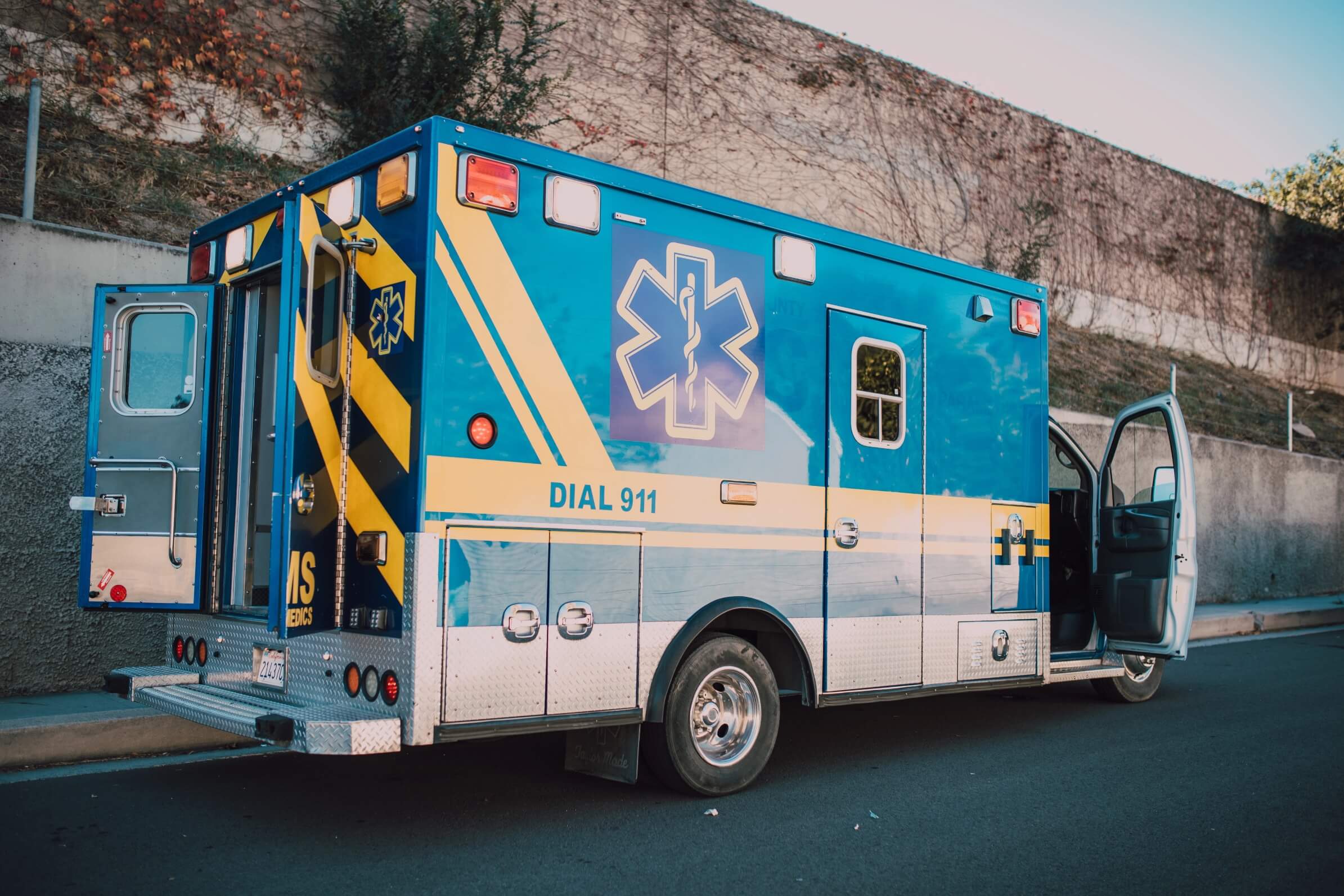 A blue and yellow ambulance parked on the side of a road.