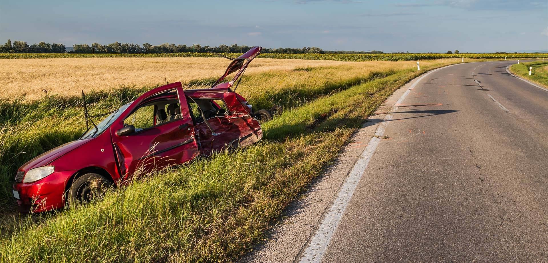 A red car that is sitting in the grass.