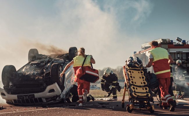 A group of people with luggage walking near some trash.